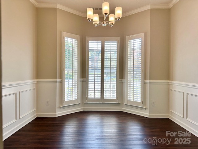 spare room with a decorative wall, a notable chandelier, and dark wood-type flooring