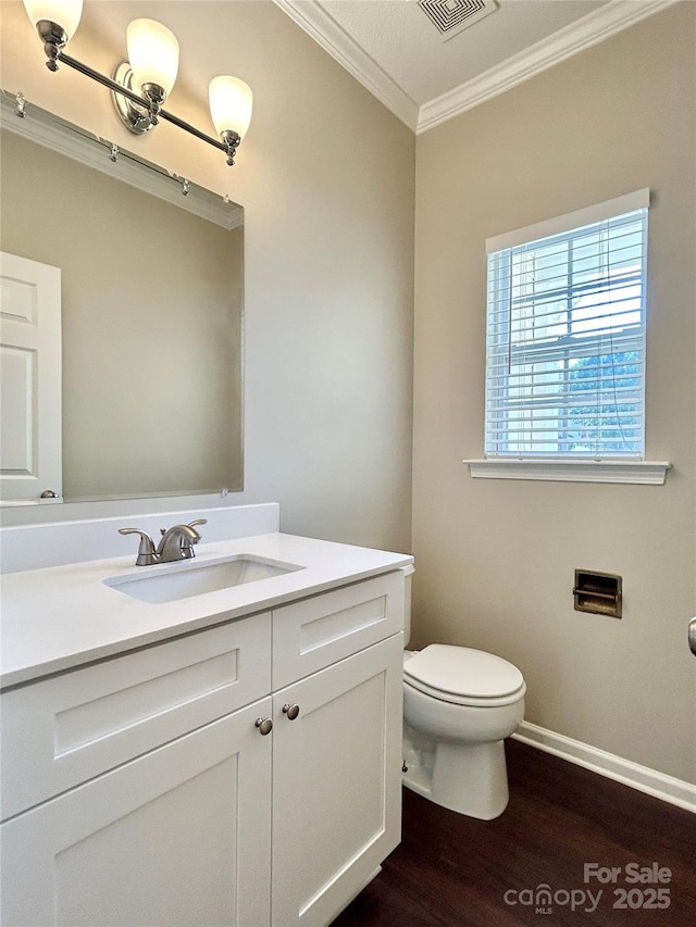 bathroom with vanity, toilet, ornamental molding, visible vents, and wood finished floors