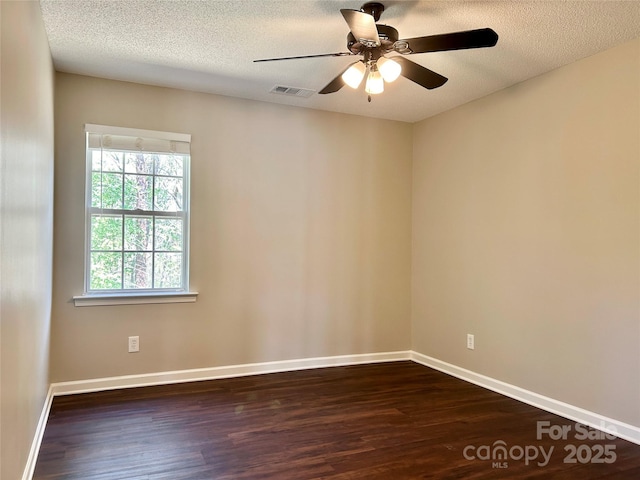 unfurnished room with a textured ceiling, dark wood-style floors, visible vents, and a ceiling fan