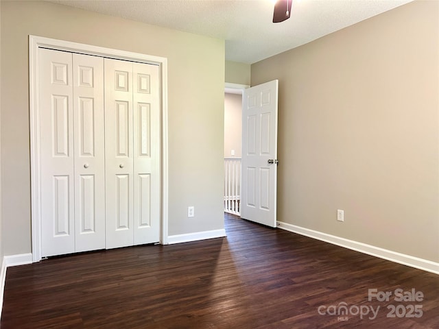 unfurnished bedroom featuring baseboards, a closet, a ceiling fan, and dark wood-style flooring