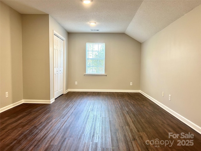 unfurnished bedroom featuring dark wood-type flooring, baseboards, a textured ceiling, and visible vents