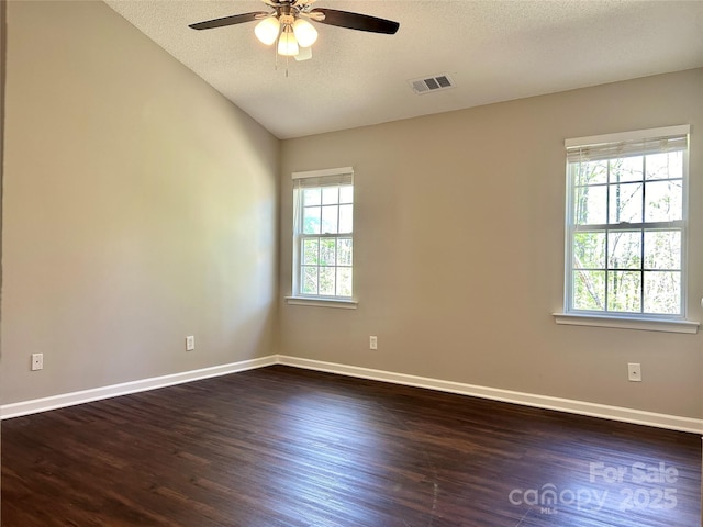 spare room featuring baseboards, dark wood-style flooring, visible vents, and a ceiling fan