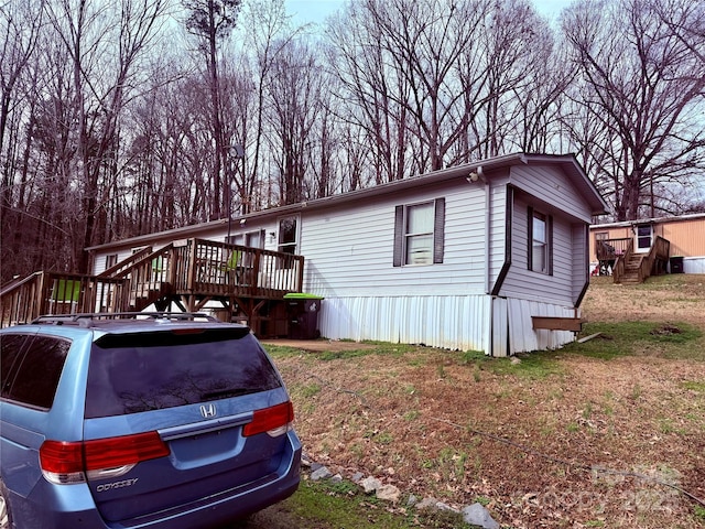 view of side of home featuring a wooden deck and a yard