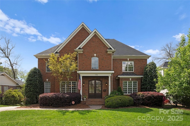 view of front of house featuring french doors, a front yard, and brick siding