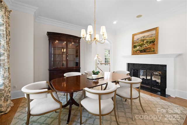 dining room with ornamental molding, wood finished floors, a multi sided fireplace, and baseboards