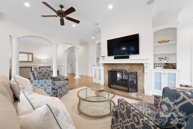 living area featuring decorative columns, a fireplace, ornamental molding, and wood finished floors