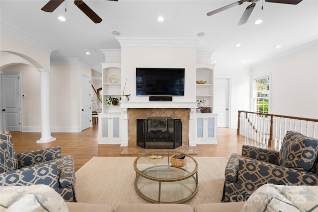 living room featuring light wood-type flooring, decorative columns, and crown molding