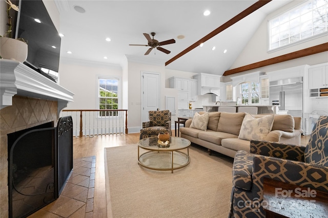 living room with a fireplace, light wood finished floors, recessed lighting, ornamental molding, and high vaulted ceiling