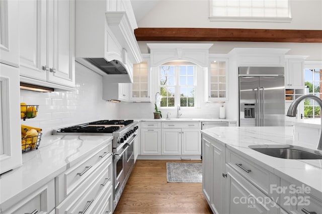 kitchen with a sink, high quality appliances, and white cabinetry