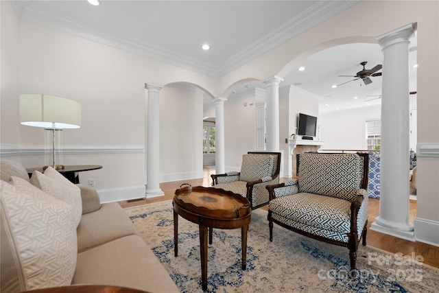 living area with ceiling fan, wood finished floors, a wealth of natural light, and ornate columns