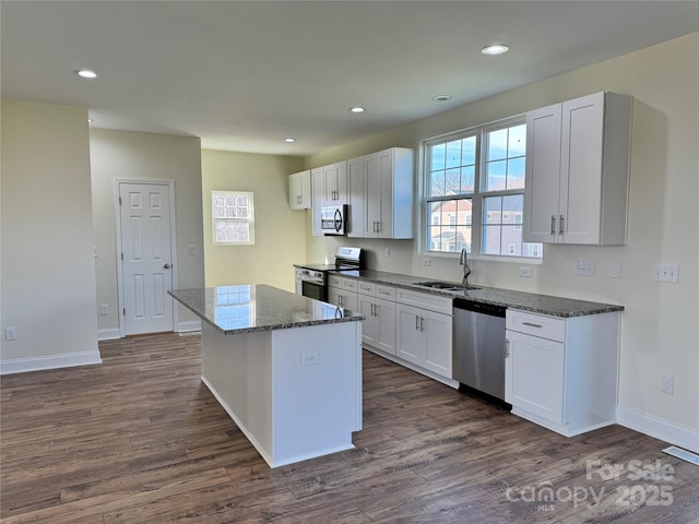 kitchen featuring a kitchen island, sink, white cabinets, dark stone counters, and stainless steel appliances