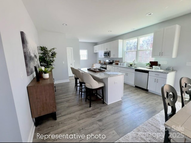 kitchen with a breakfast bar, appliances with stainless steel finishes, a center island, and white cabinets