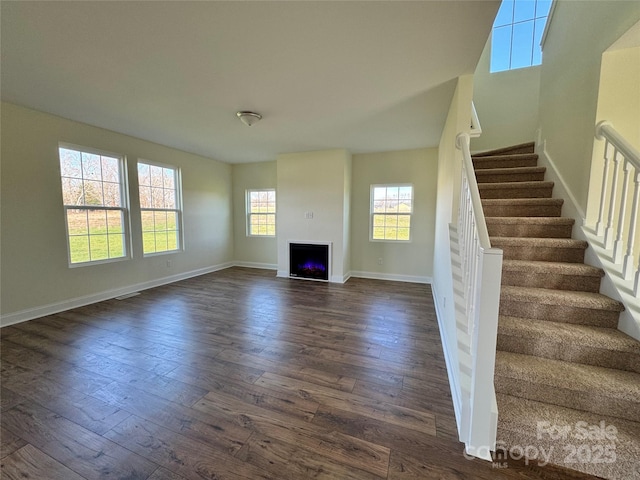 1022 Heath Helms Rd, Monroe, NC 28110 - unfurnished living room featuring dark wood-style floors, stairway, baseboards, and a lit fireplace