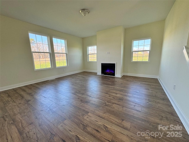 1022 Heath Helms Rd, Monroe, NC 28110 - unfurnished living room featuring plenty of natural light, dark wood-style floors, a warm lit fireplace, and baseboards