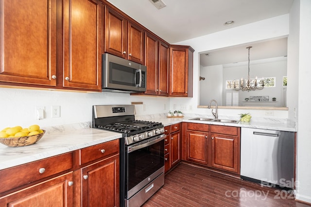 kitchen with hanging light fixtures, stainless steel appliances, light stone counters, dark hardwood / wood-style flooring, and sink