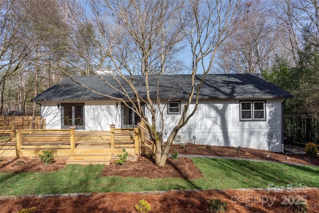 view of front facade with a shingled roof and a wooden deck