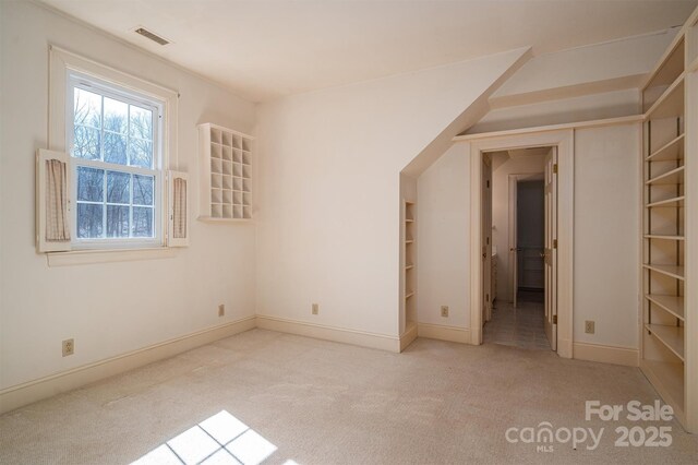 interior space featuring baseboards, visible vents, and light colored carpet