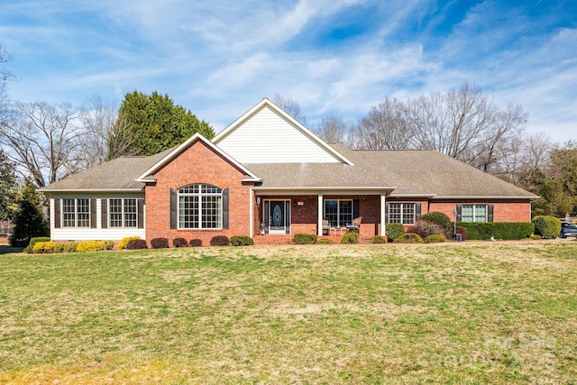 ranch-style house featuring roof with shingles, a porch, a front lawn, and brick siding