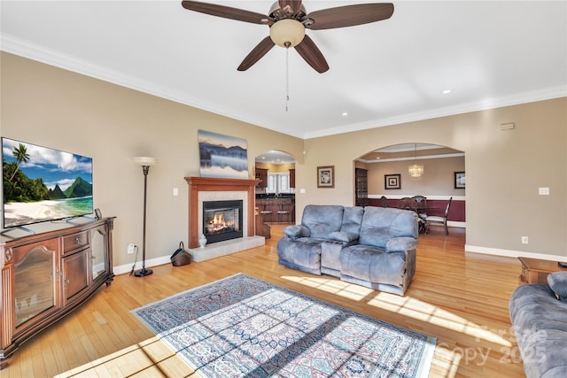119 Era St, Troutman, NC 28166 - living room with arched walkways, light wood finished floors, crown molding, a tile fireplace, and a ceiling fan