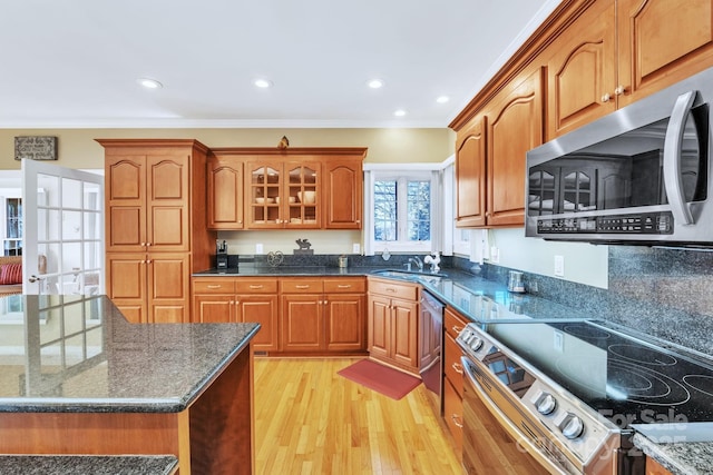 119 Era St, Troutman, NC 28166 - kitchen featuring stainless steel appliances, dark stone counters, brown cabinetry, light wood-style floors, and crown molding
