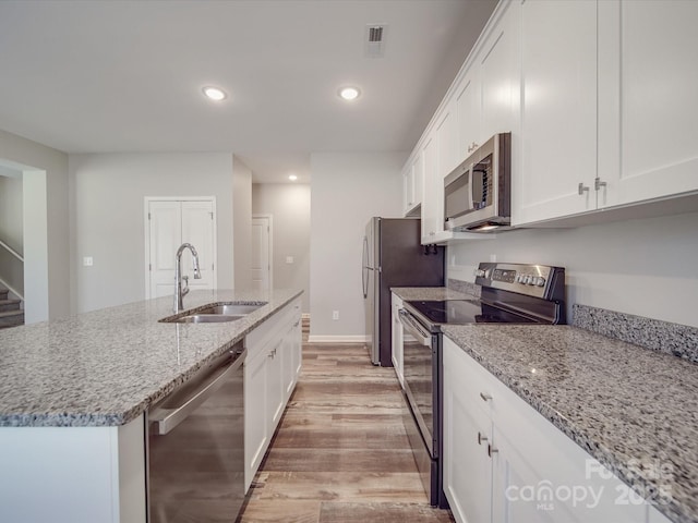 kitchen with white cabinets, stainless steel appliances, light stone countertops, and sink