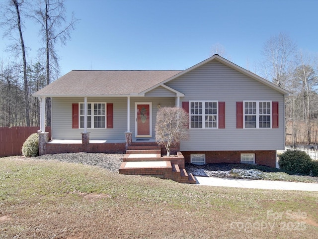 view of front facade with a shingled roof, fence, and a front lawn