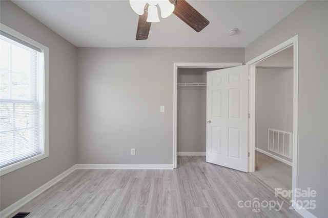 unfurnished bedroom with light wood-style flooring, multiple windows, visible vents, and baseboards