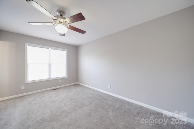 carpeted empty room with a ceiling fan, visible vents, and baseboards