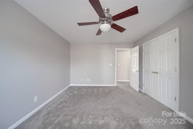 unfurnished bedroom with a closet, baseboards, a ceiling fan, and light colored carpet