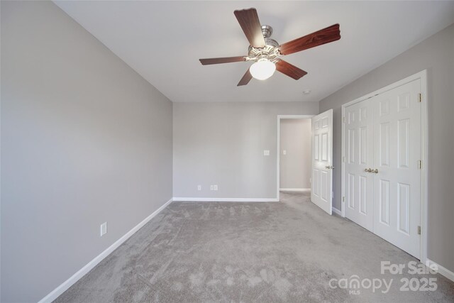 unfurnished bedroom featuring light carpet, ceiling fan, baseboards, and a closet