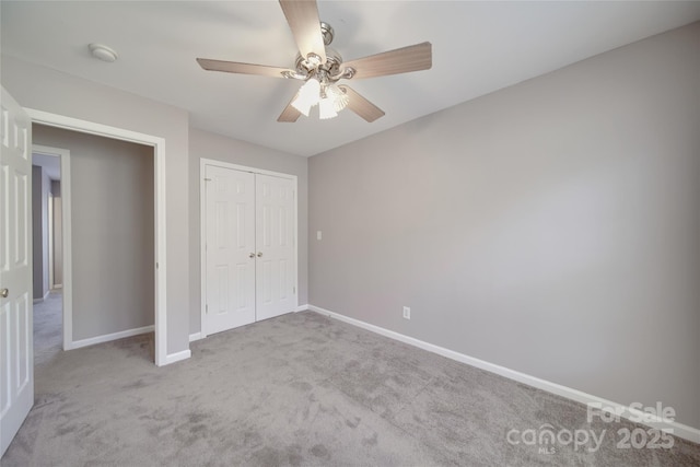 unfurnished bedroom featuring a closet, light colored carpet, ceiling fan, and baseboards