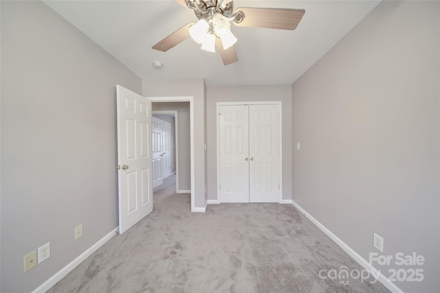 unfurnished bedroom featuring a ceiling fan, a closet, light colored carpet, and baseboards