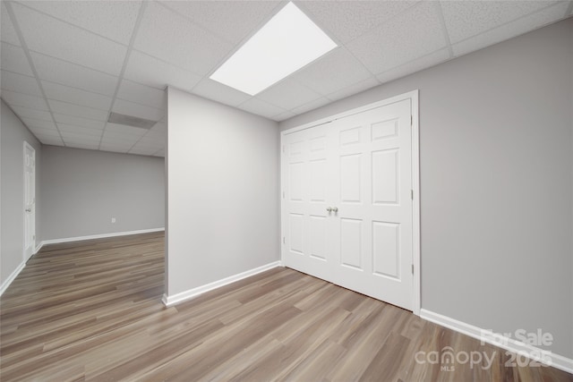 finished below grade area featuring a drop ceiling, wood finished floors, and baseboards