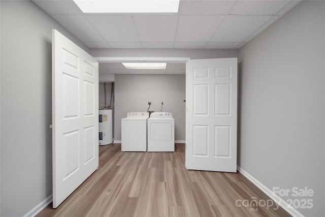 laundry room featuring light wood finished floors, washing machine and clothes dryer, electric water heater, laundry area, and baseboards