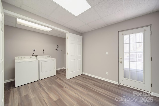 washroom featuring laundry area, wood finished floors, baseboards, and separate washer and dryer