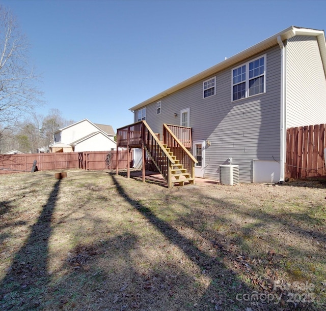 rear view of house featuring a wooden deck, stairway, fence, and a lawn