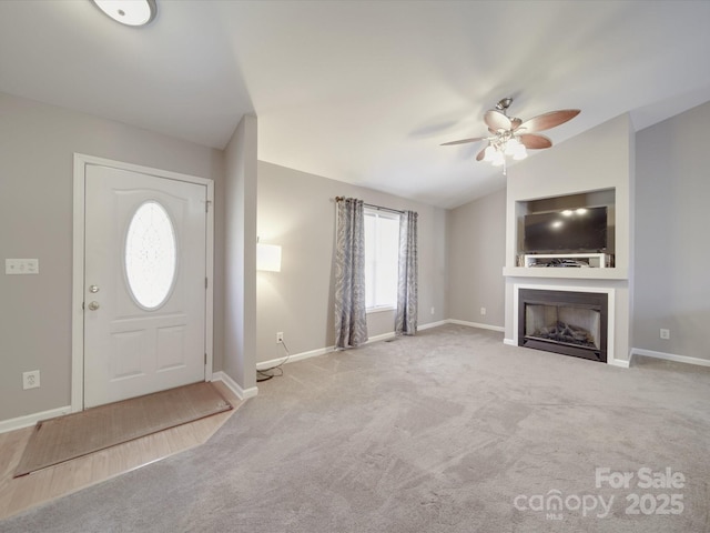 entryway featuring baseboards, light carpet, vaulted ceiling, and a fireplace