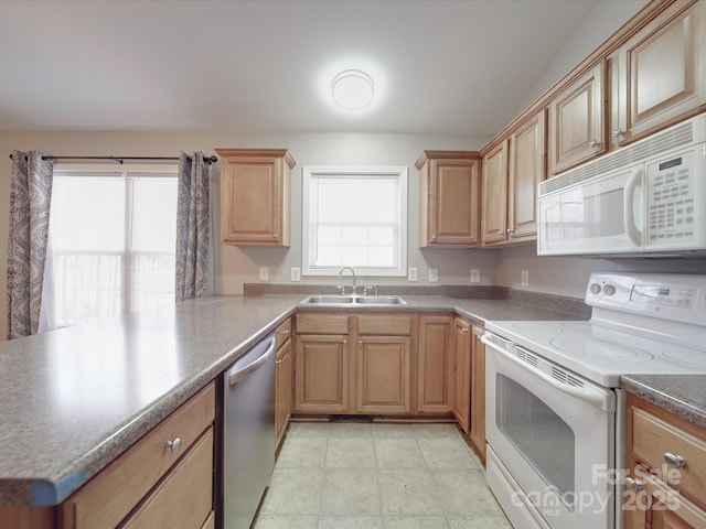 kitchen featuring plenty of natural light, white appliances, a sink, and dark countertops