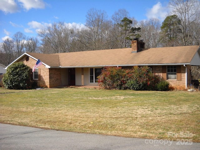 ranch-style home featuring a chimney, a front lawn, and brick siding