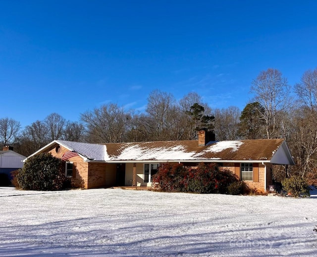 single story home featuring a chimney and brick siding