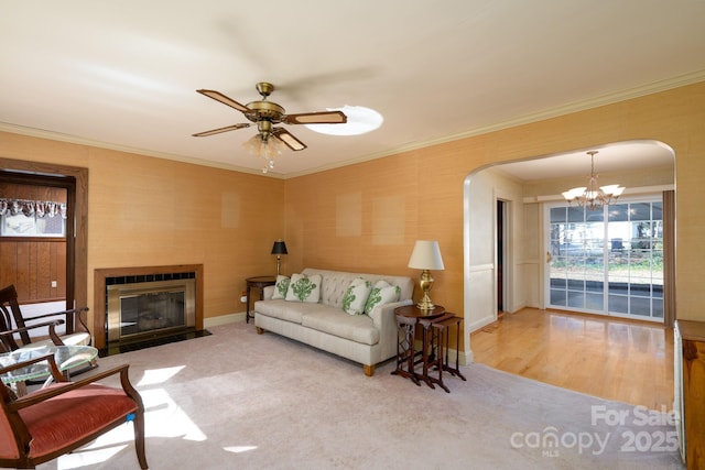 living room featuring carpet, ornamental molding, and ceiling fan with notable chandelier