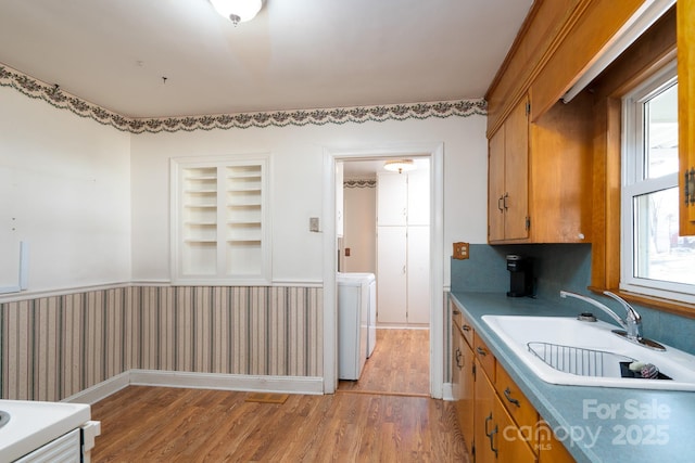 kitchen with sink, washer / dryer, light wood-type flooring, and built in features