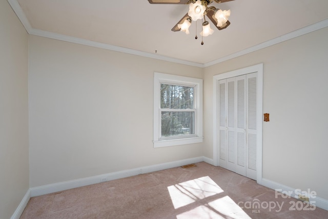 unfurnished bedroom with light carpet, ceiling fan, a closet, and crown molding