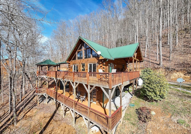 rear view of house with metal roof, a wooden deck, and log siding