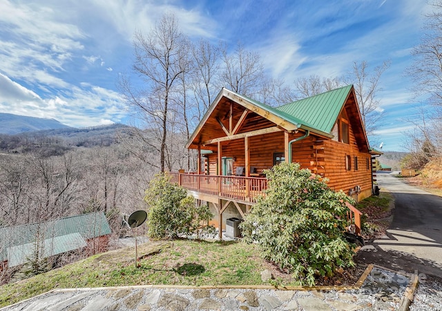 exterior space featuring log exterior, metal roof, a standing seam roof, central air condition unit, and a mountain view