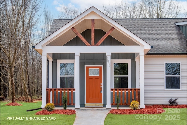 view of front facade featuring covered porch, a front lawn, roof with shingles, and board and batten siding