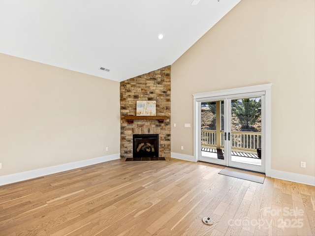 unfurnished living room with high vaulted ceiling, a fireplace, and light hardwood / wood-style floors