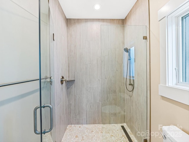 bathroom featuring toilet and a shower with shower door