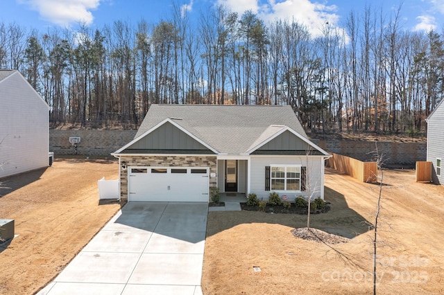 view of front facade featuring a garage, concrete driveway, roof with shingles, fence, and board and batten siding