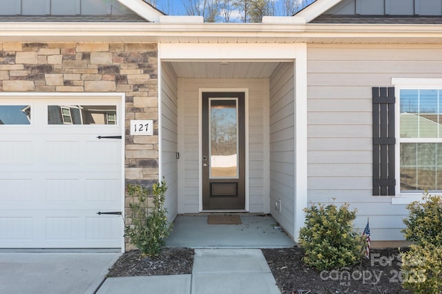 doorway to property with a garage, stone siding, and board and batten siding